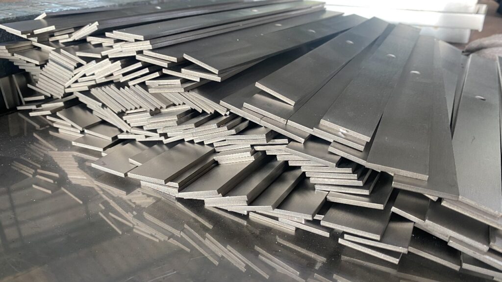 Stainless steel flat bars stacked on a reflective surface, with precise edges and uniform thickness. The image captures the durability and versatility of flat bars for industrial applications